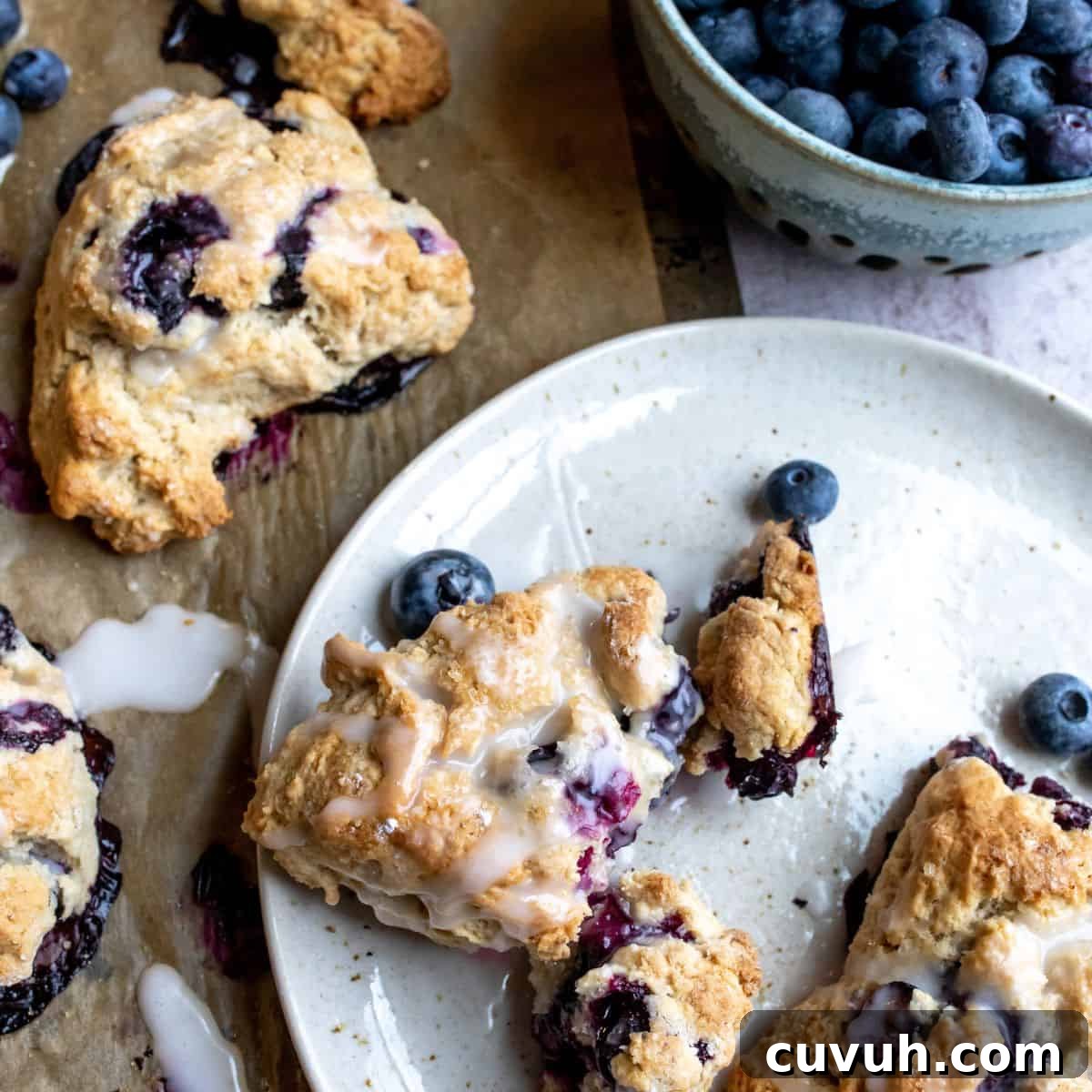 Blueberry Cardamom Scones Recipe — Flaky, Aromatic Breakfast Treat 2 Blueberry Cardamom Scones up close on a plate with icing.