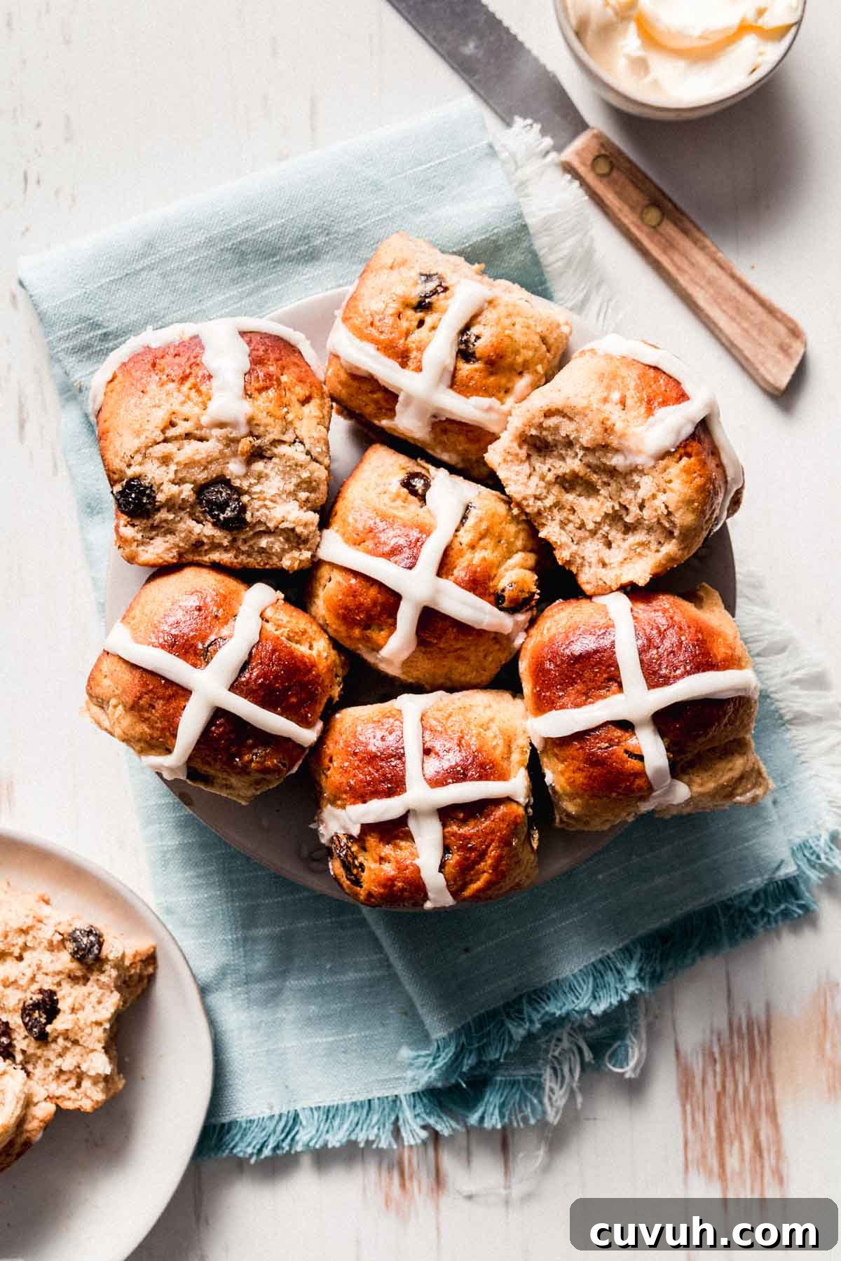 A plate with gluten-free hot cross buns spilling over the edges. One split to the side.