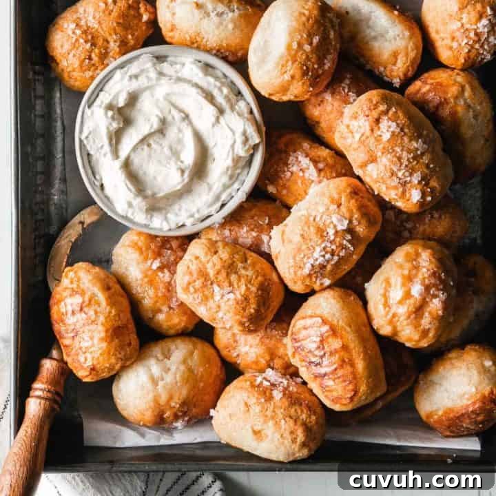 Gluten-free soft pretzel bites made with three ingredient dough in a small pan next to cream cheese.