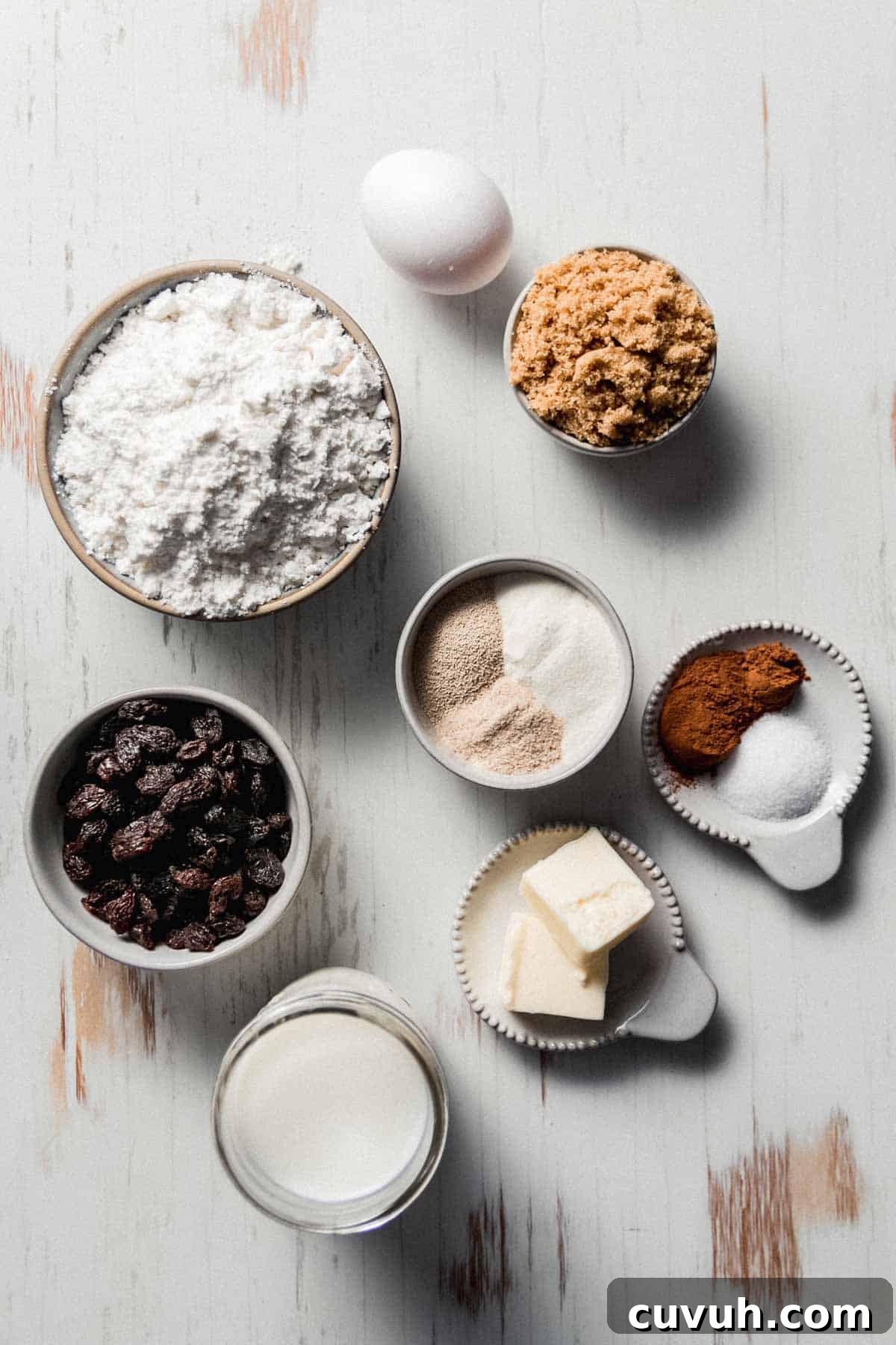 Ingredients measured in bowls including gluten-free flour, raisins, butter, sugar, egg, and spices.