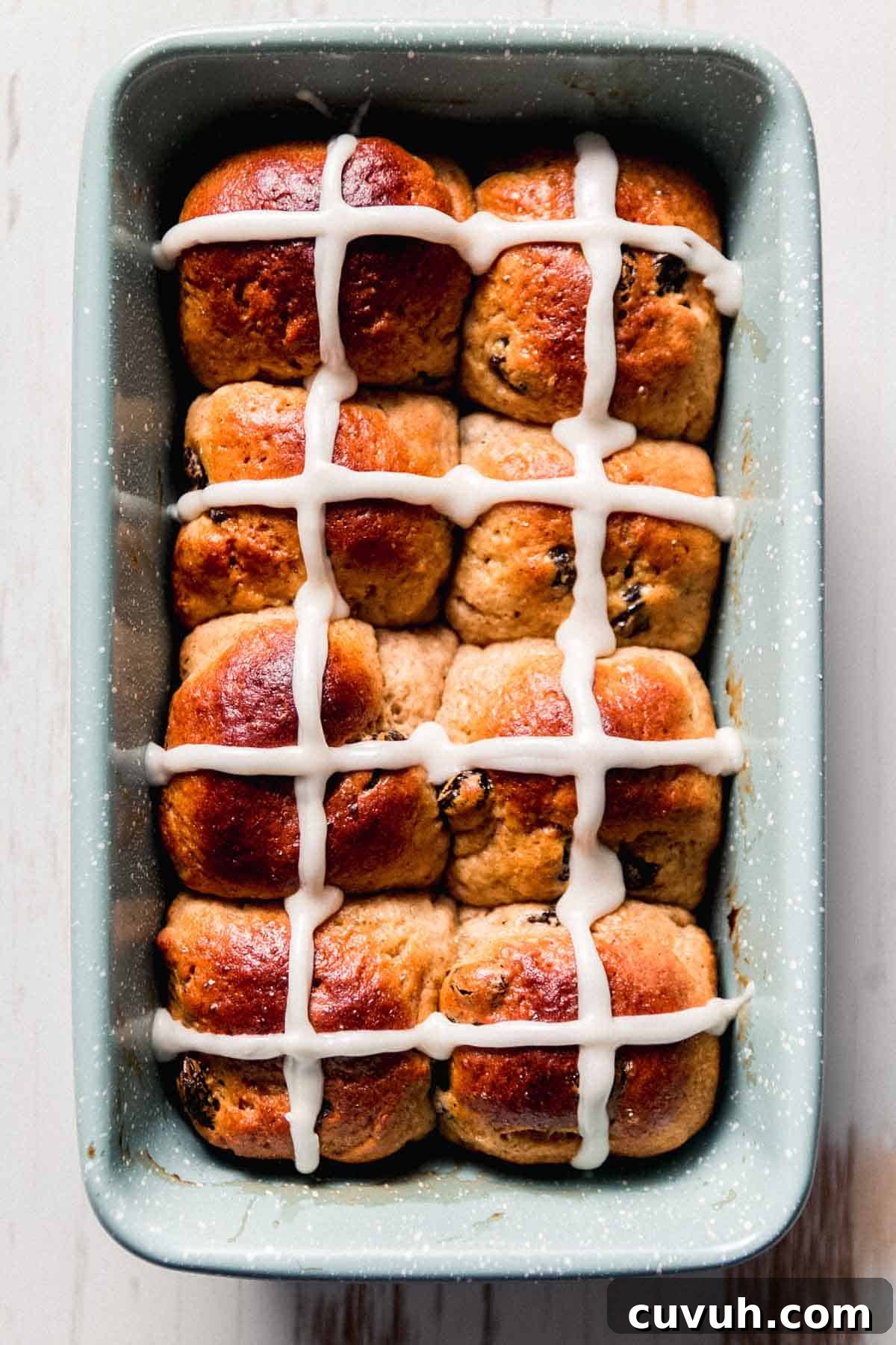 A speckled green loaf pan with iced hot cross buns.