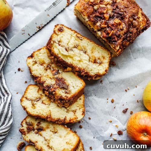 Apple bread laid out on white parchment paper and partially sliced.