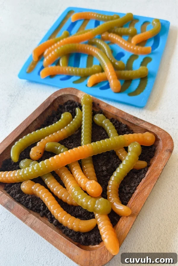 Gummy worms served on a plate with crushed up cookies.