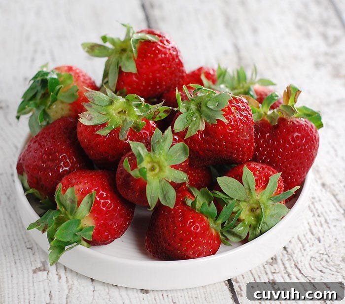 a small white plate filled with strawberries, sitting on a wooden table painted in white