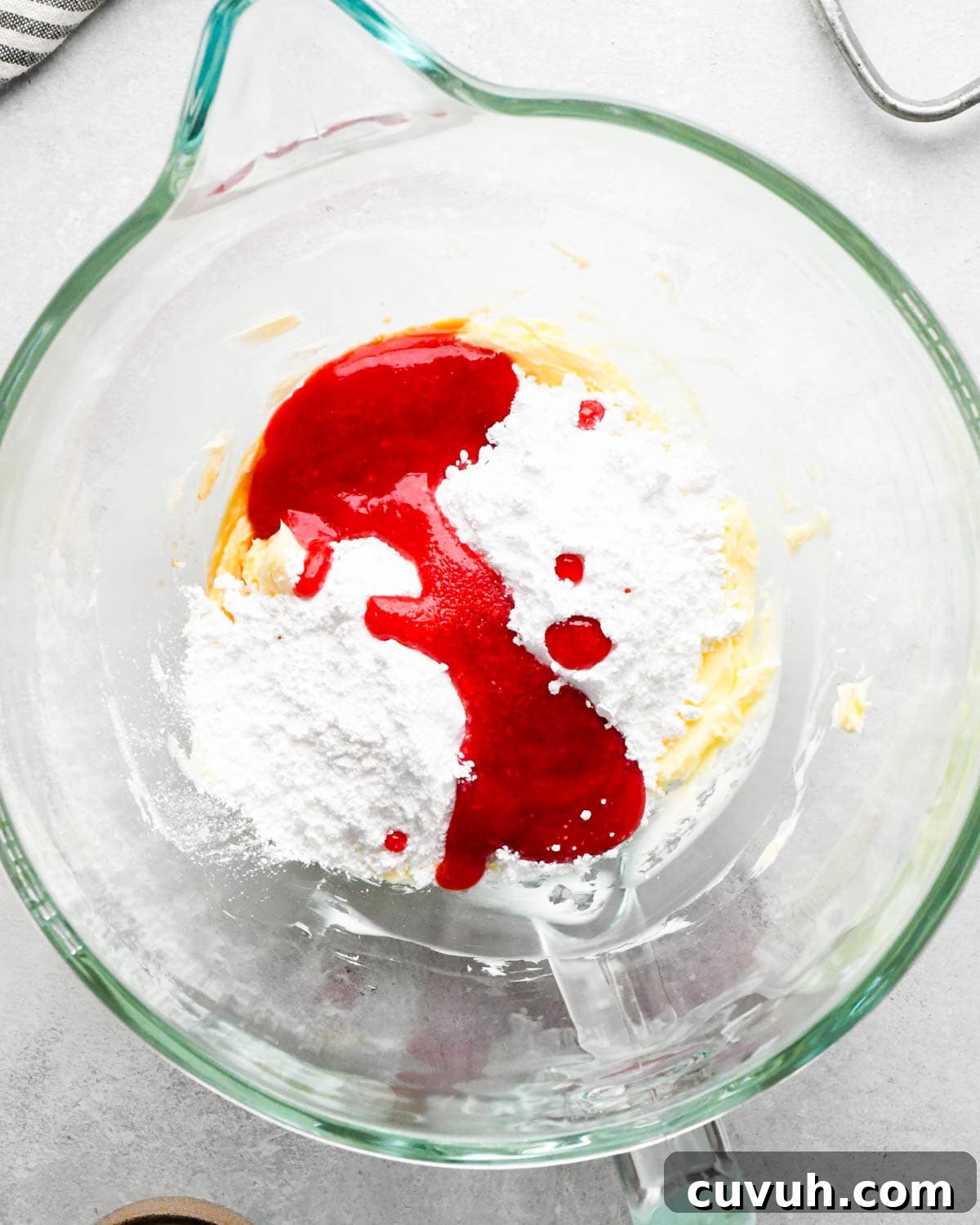 how to make raspberry frosting - raspberry puree and powdered sugar added to the beaten butter in a glass mixing bowl before mixing