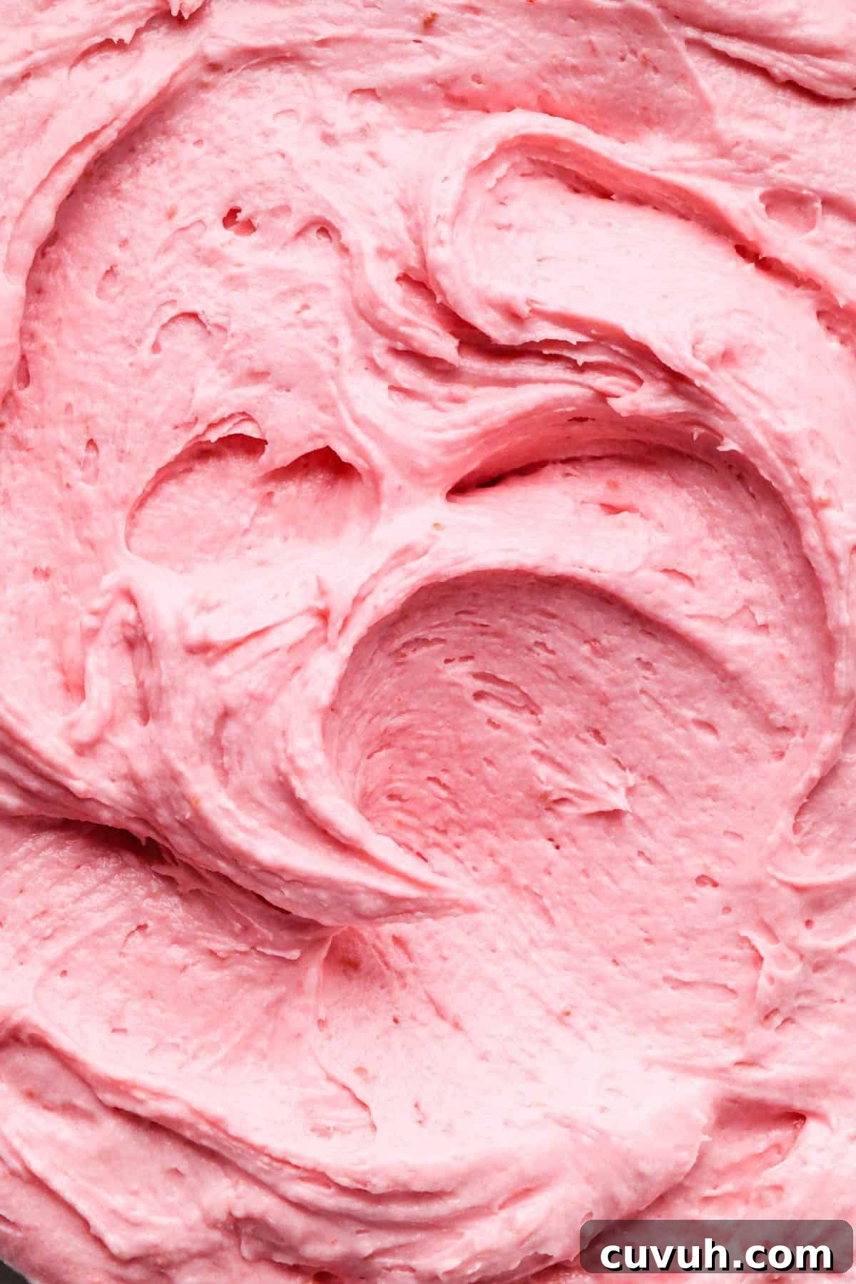 up close macro photo of swirls of raspberry buttercream frosting 