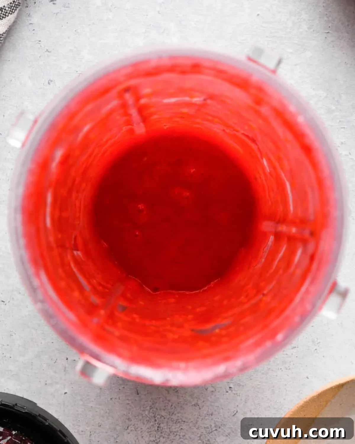 how to make raspberry frosting - raspberries and sugar in a small blending container after blending overhead view