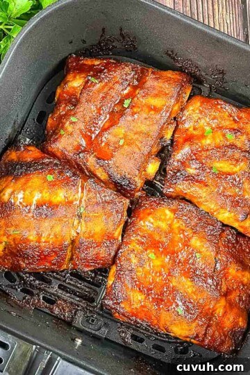 Air Fryer spare ribs covered in barbecue sauce in the air fryer basket.
