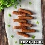 Crispy Juicy Air Fryer Breakfast Sausages in 15 Minutes 13 Air fryer sausages placed on parchment paper with a bunch of cilantro in the background.