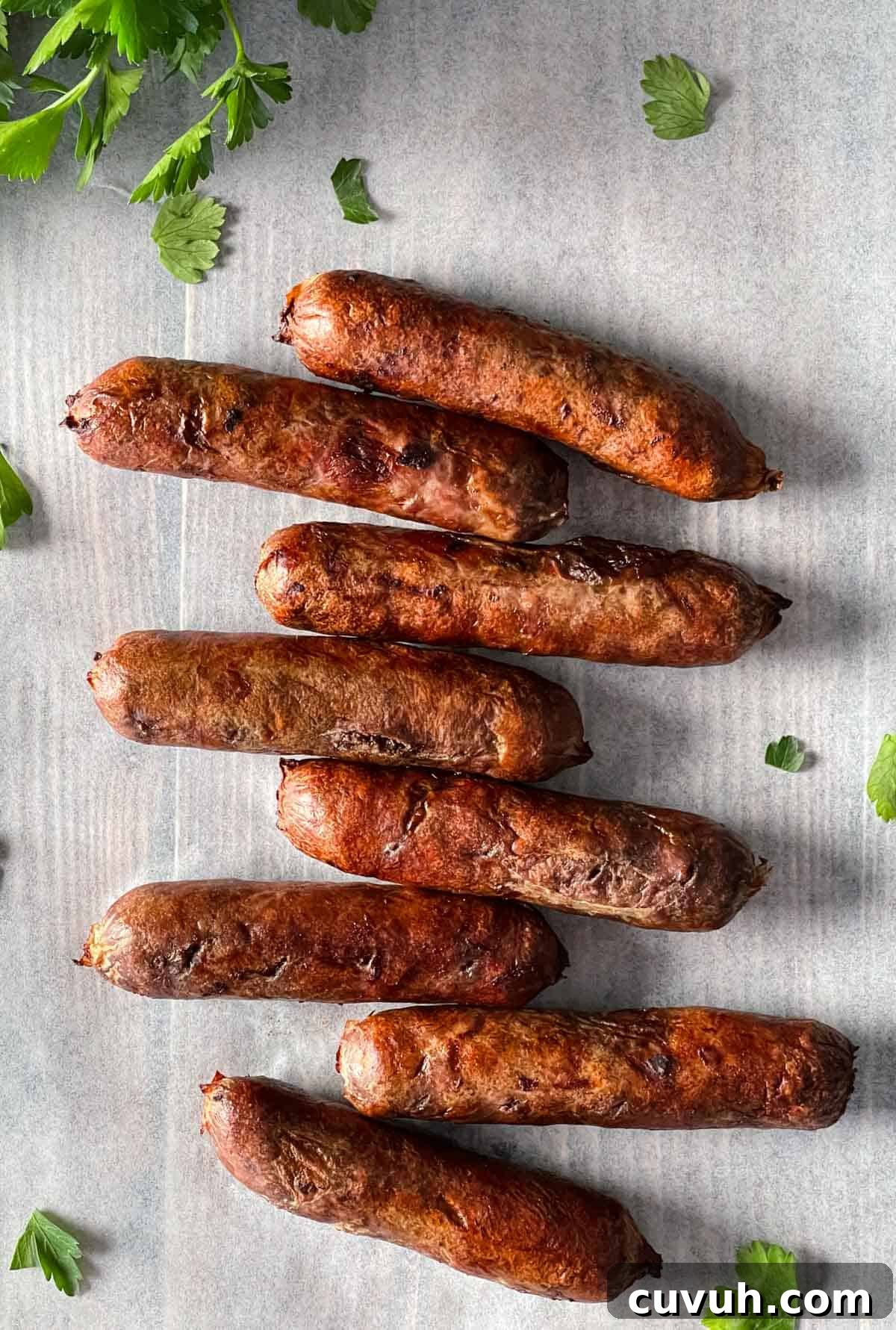 Crispy Juicy Air Fryer Breakfast Sausages in 15 Minutes 8 Cooked breakfast sausages on parchment paper.