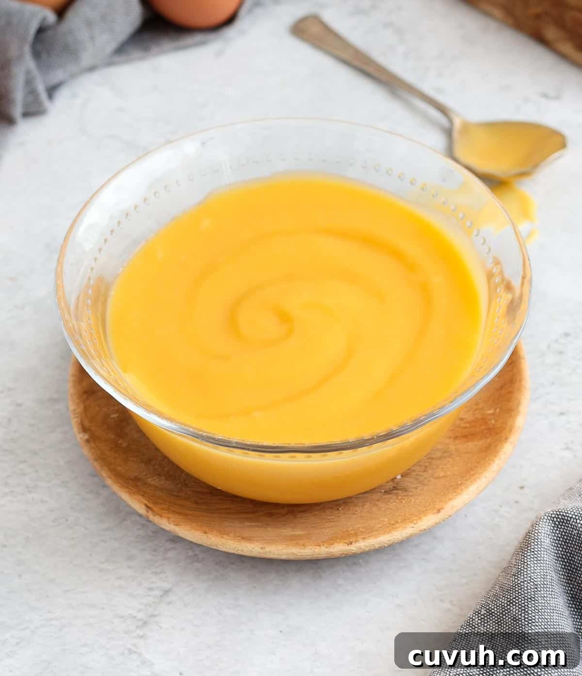 Curd placed in a glass bowl over a wooden plate.
