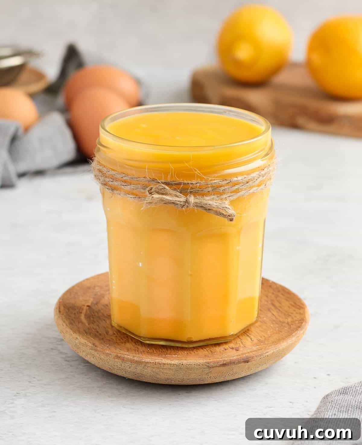 Glass are filled with curd with lemons and eggs in the background.