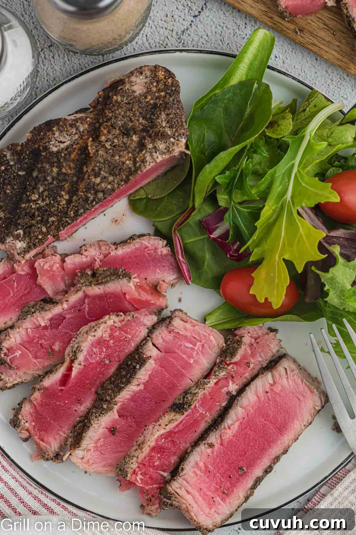 Perfectly Grilled Tuna Steaks: Marinade, Sear & Serving Tips 7 Sliced Grilled Tuna steaks on a plate with side salad