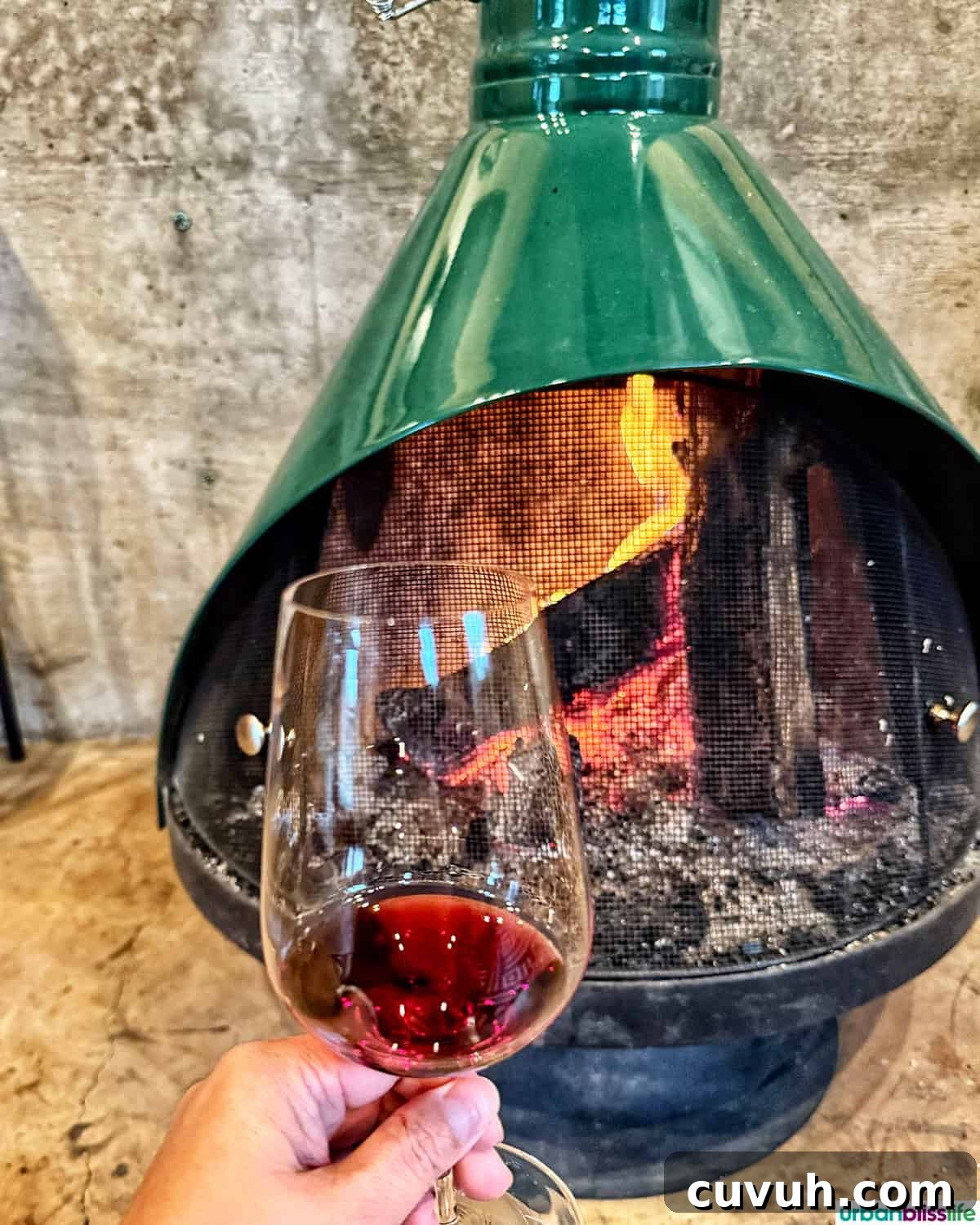 glass of red wine in front of a green fireplace.