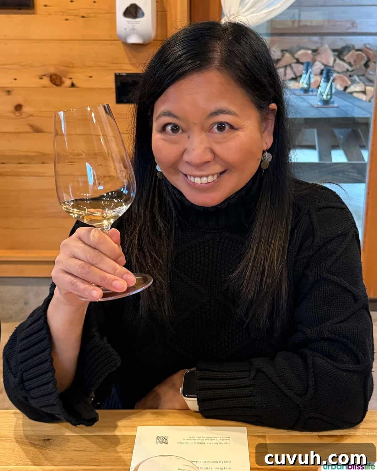 Marlynn holding a glass of white wine in Evening Land Vineyards wine tasting cabin.
