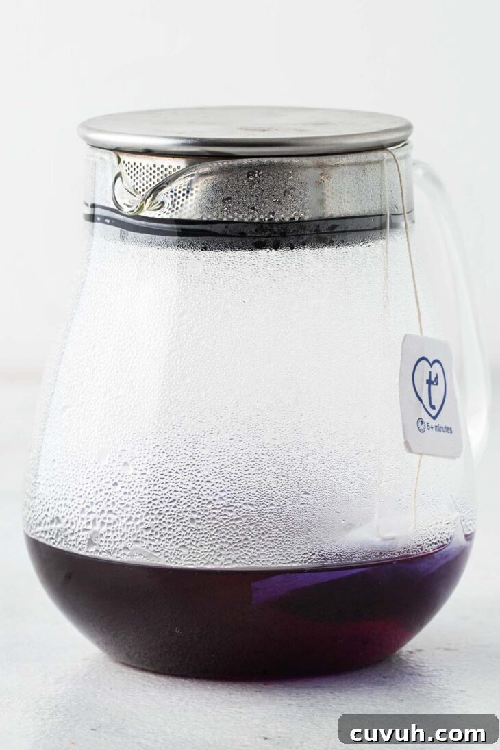 Steeping butterfly pea flower tea in hot water in a teapot.
