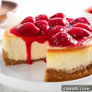 Decadent Strawberry Cheesecake Recipe with Fresh Berry Topping 19 Strawberry cheesecake with strawberry topping flowing down the sides.