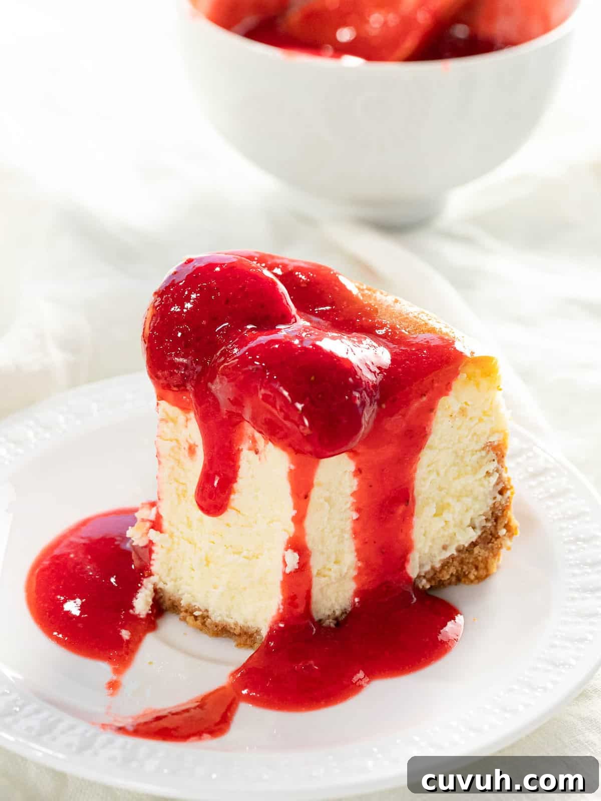Decadent Strawberry Cheesecake Recipe with Fresh Berry Topping 4 Bite taken out of a slice of strawberry cheesecake.