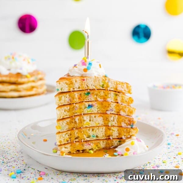 Stack of birthday cake pancakes, cut like cake, with a candle.