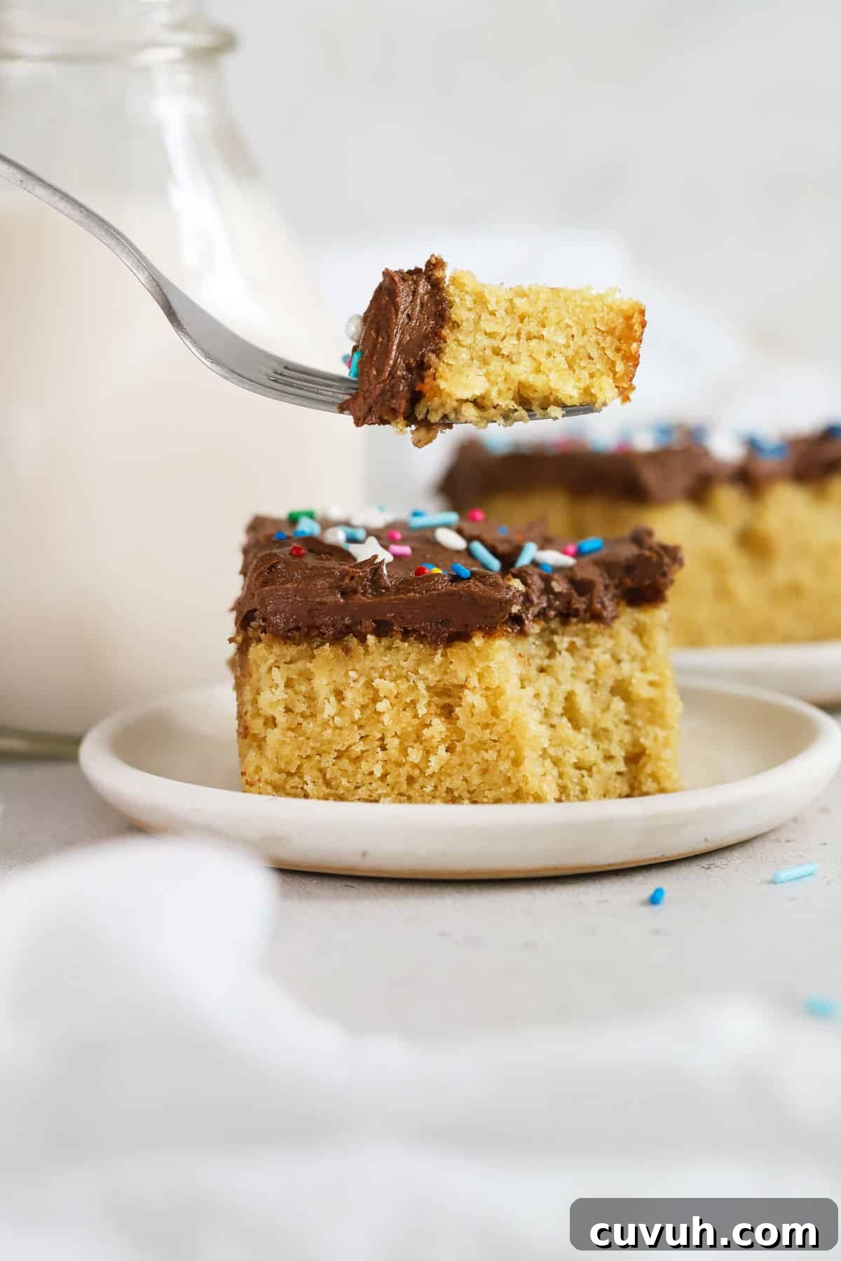 Moist Gluten-Free Yellow Sheet Cake Recipe for Parties 9 A fork taking a bite out of a slice of gluten-free yellow sheet cake