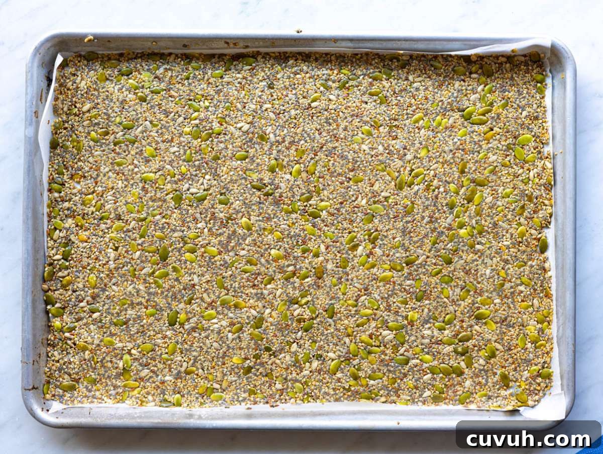 Crispy Seed Crackers: Flour-Free Savory Snack Recipe 6 Step 2 Seed cracker mixture spread thin and evenly on a parchment-lined baking sheet.