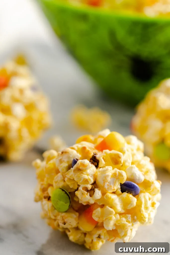 Close up of a popcorn ball with purple and green M&M's.