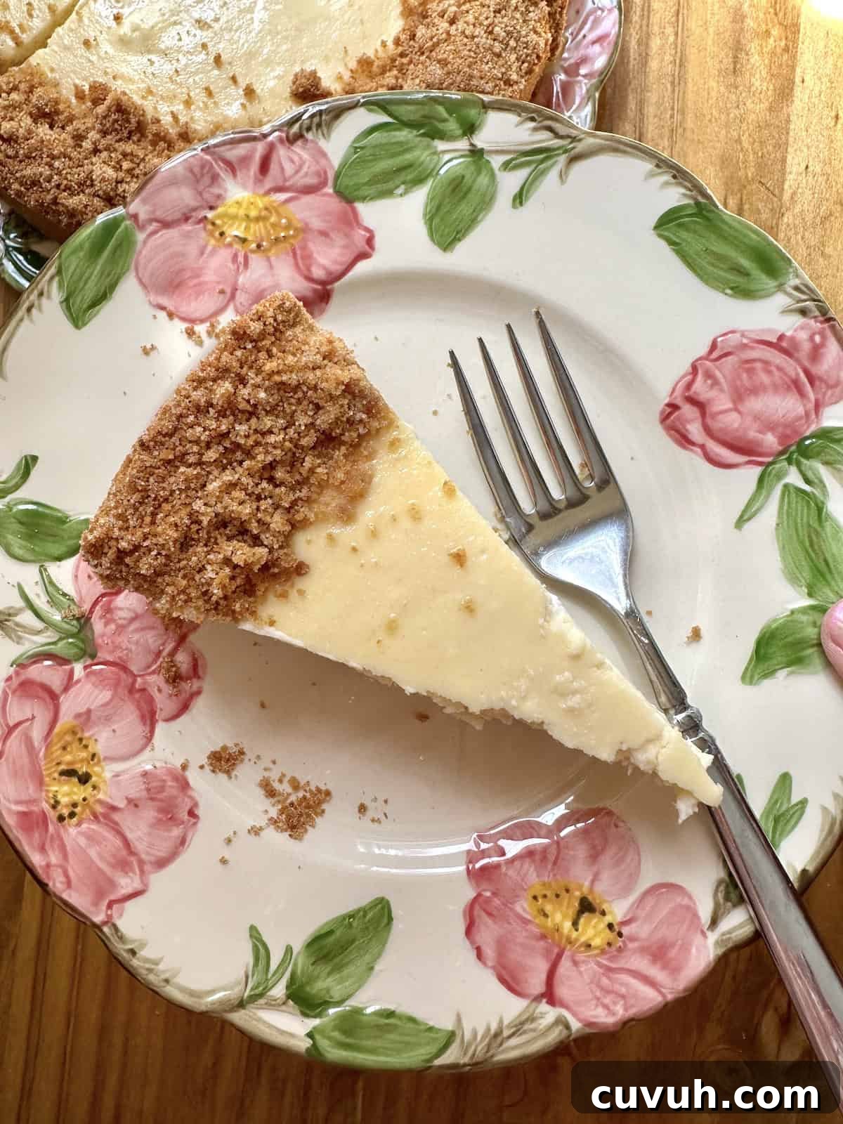 A slice of vanilla cheesecake on a plate with a fork.