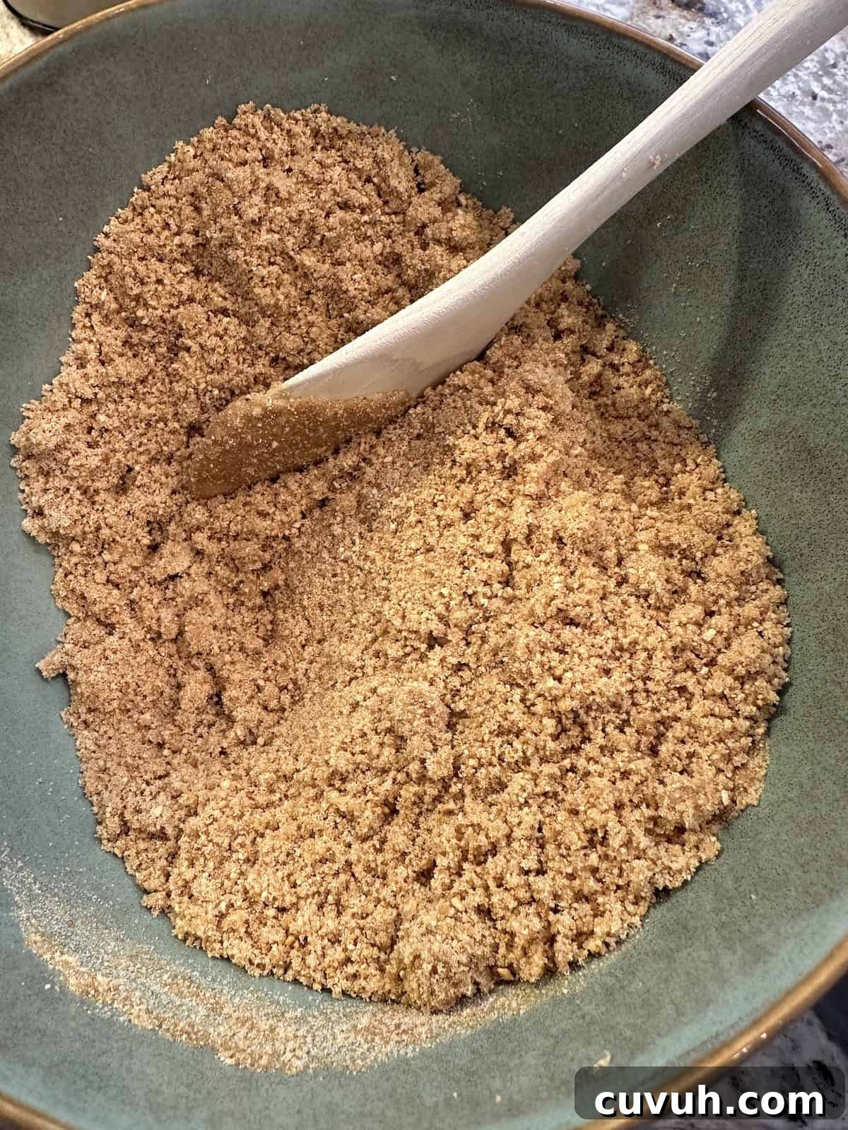 Graham cracker crust ingredients in a bowl with a wooden spoon on the side.