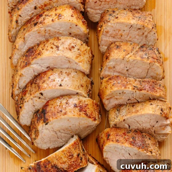 Sliced cast iron pork tenderloin on a wood board with a fork.