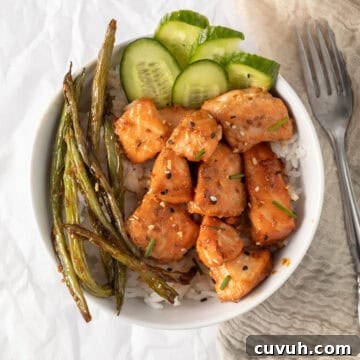 salmon bites in a rice bowl with cucumber and green beans.