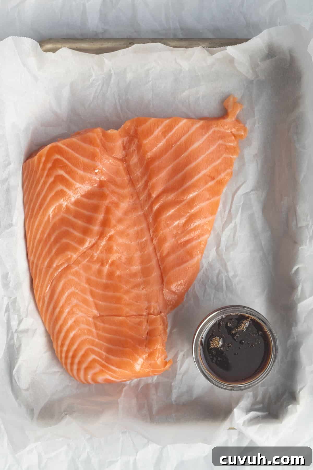 salmon and soy sauce on a parchment lined sheet pan.