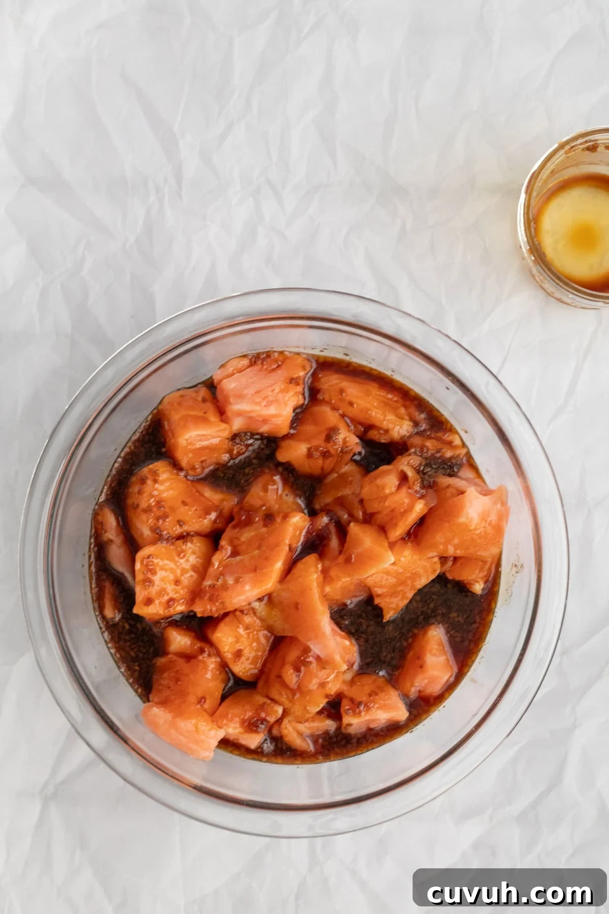 salmon marinating in a glass bowl.