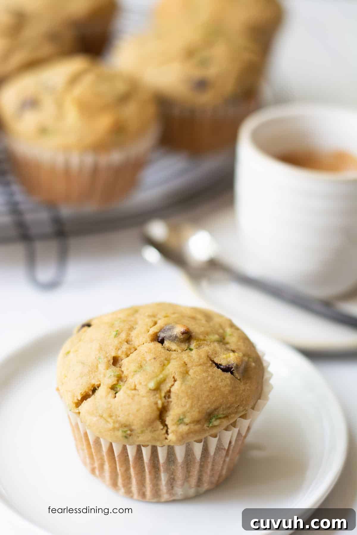 A gluten-free zucchini muffin on a plate next to an espresso.