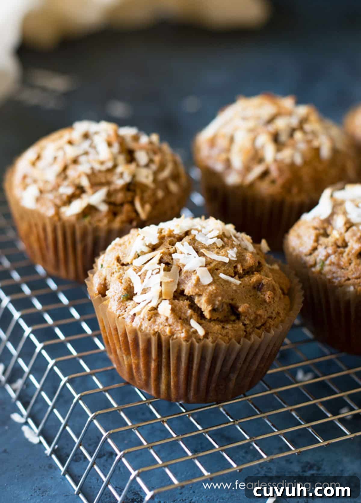Four zucchini muffins on a wire rack.