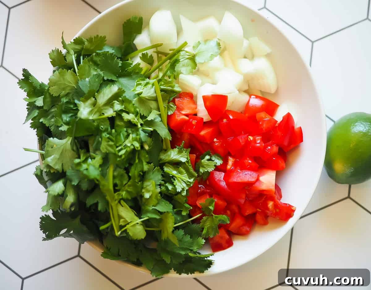 Fresh Garden Salsa Ready in 5 Minutes 4 A white bowl with onion, tomato, and cilantro in it with a lime.