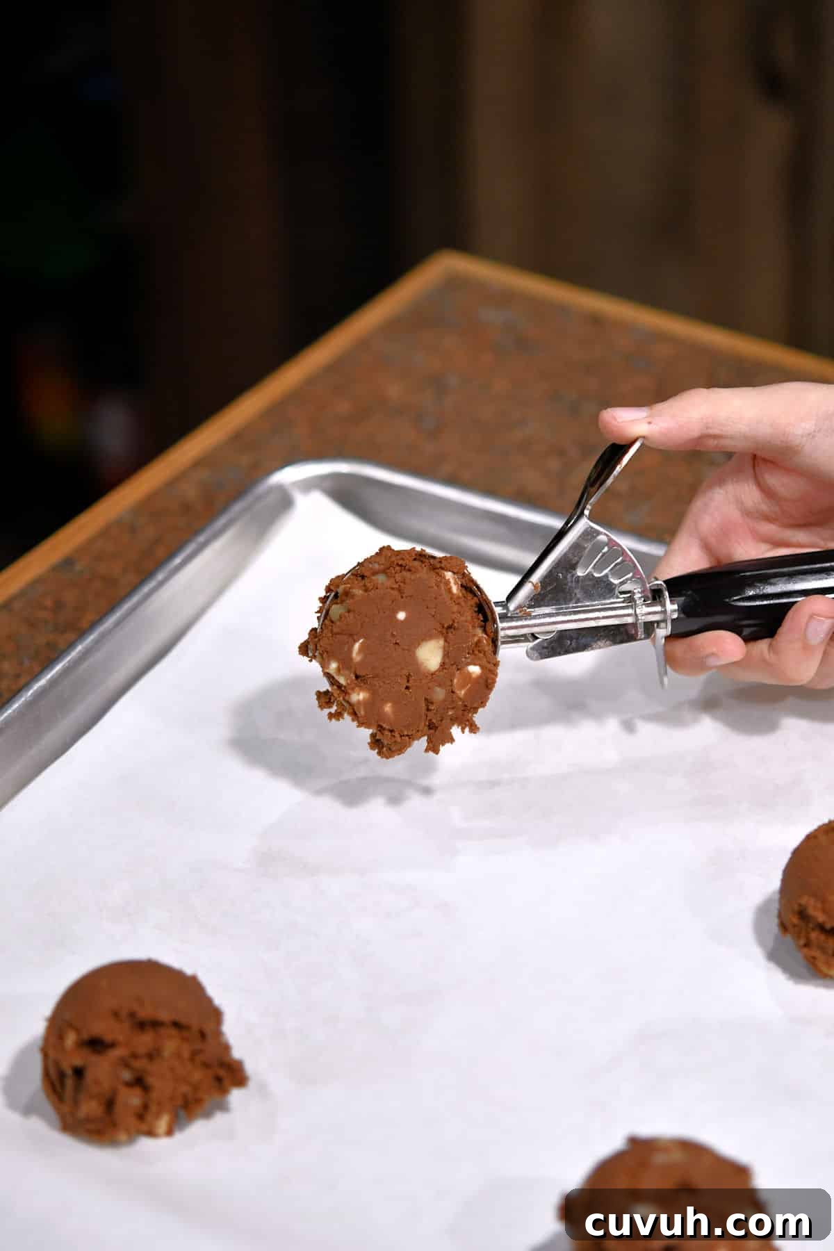 Chewy Chocolate Macadamia Nut Cookies Recipe 5 scooping chocolate cookie dough onto white parchment paper