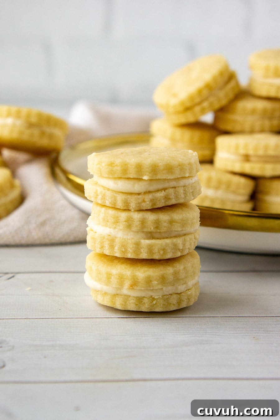 a stack of maple sandwich cookies in front of a plate of more cookies.