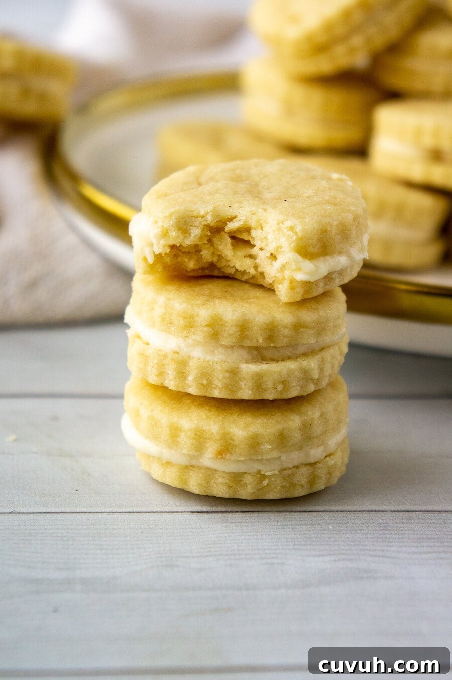 maple sandwich cookies stacked three high with the top missing a bite.