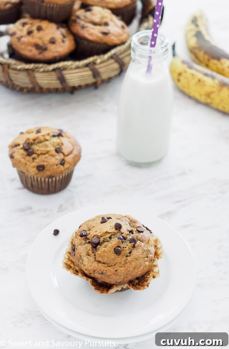 Banana Oatmeal Chocolate Chip Muffin on small white dish served with small bottle of milk.