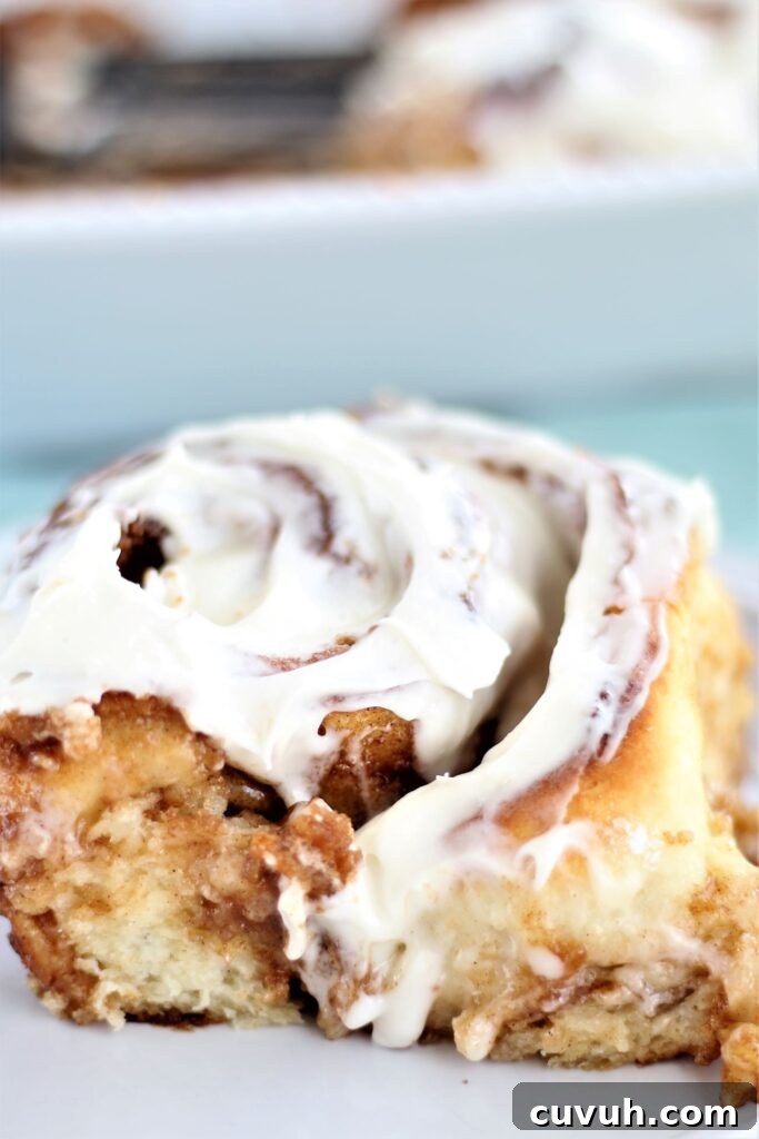 large cinnamon roll with icing on white plate
