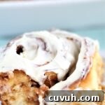 large cinnamon roll with icing on white plate