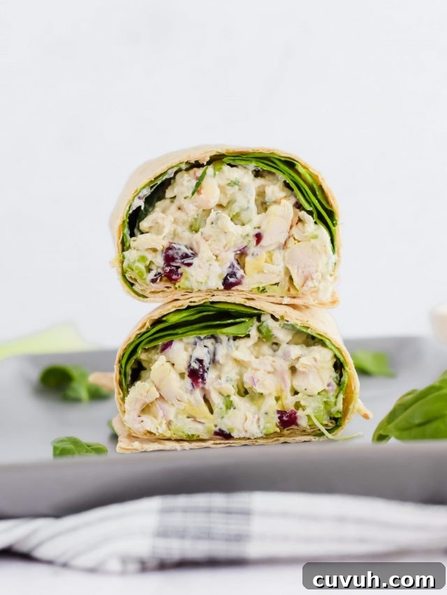 sliced wrap stacked on top of each other, filled with chicken salad and spinach on concrete plate