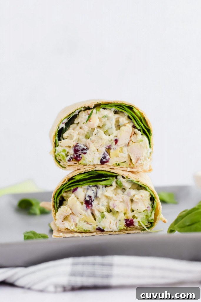 sliced wrap stacked on top of each other, filled with chicken salad and spinach on concrete plate