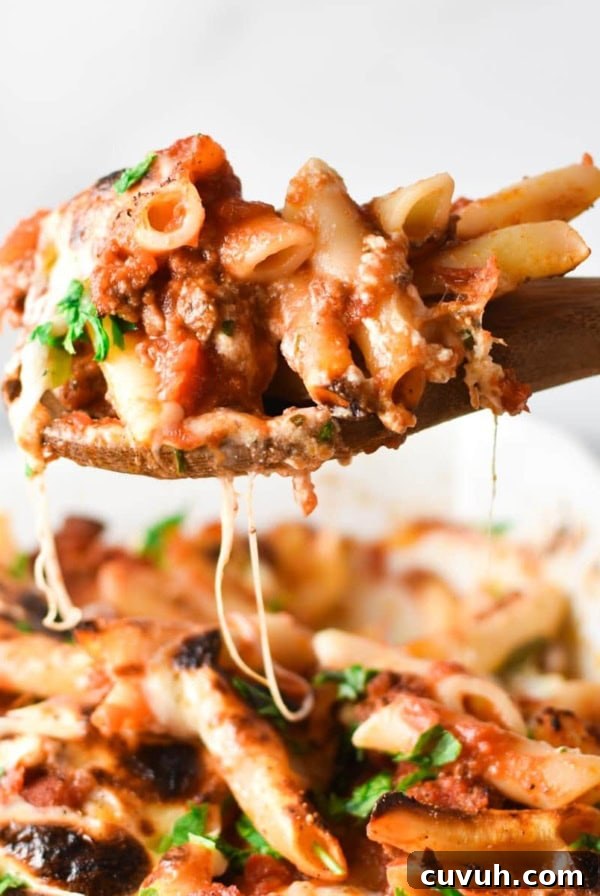 A scoop of lazy lasagna on a wooden spoon over a casserole dish with strings of cheese hanging off