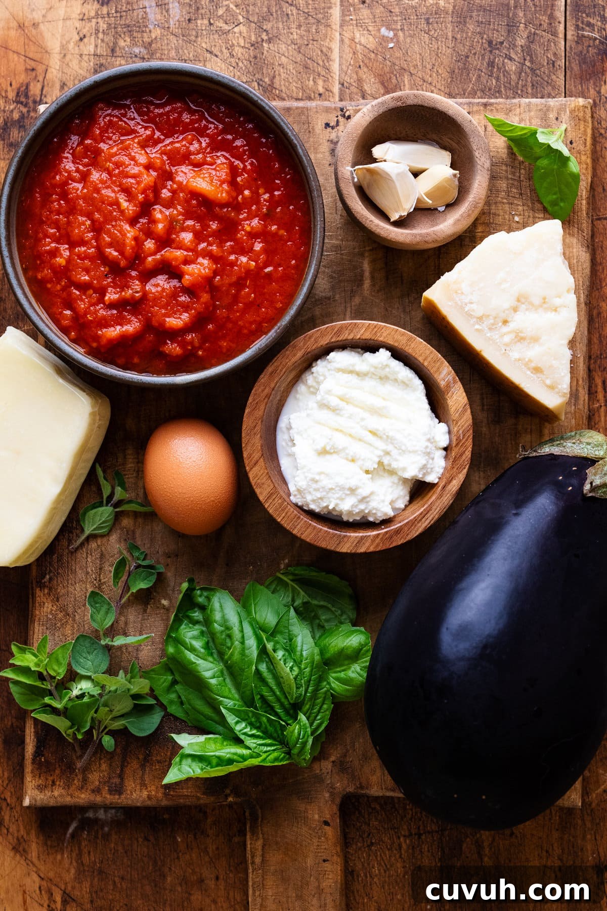 Ingredients for eggplant lasagna arranged on a wooden cutting board.