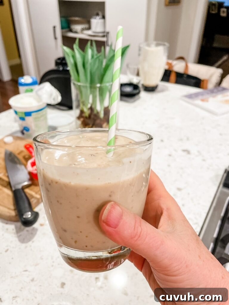 Creamy Date & Banana Protein Smoothie Recipe for Energy 2 Marie holding up the finished Date and Banana Protein Smoothie with a straw