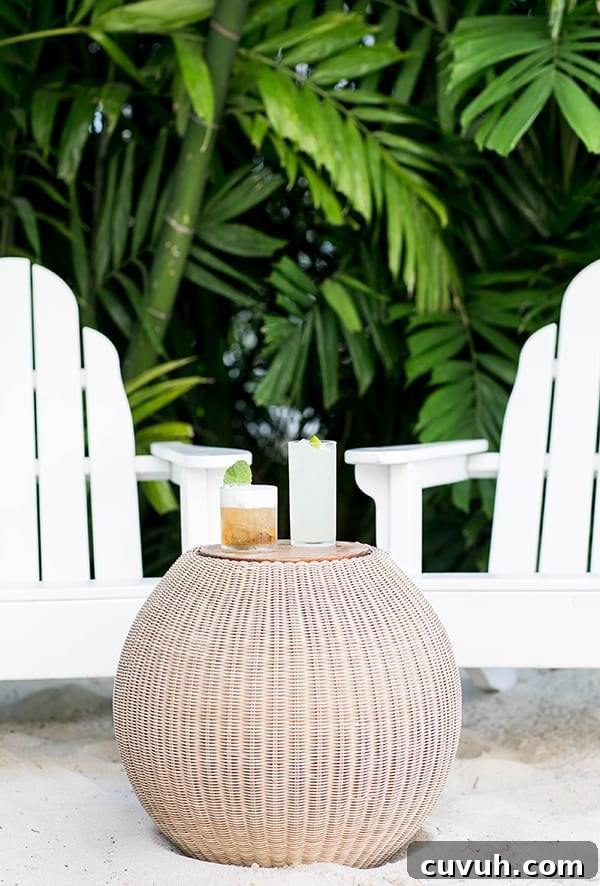 Two chairs and on a beach with a table and cocktails. 