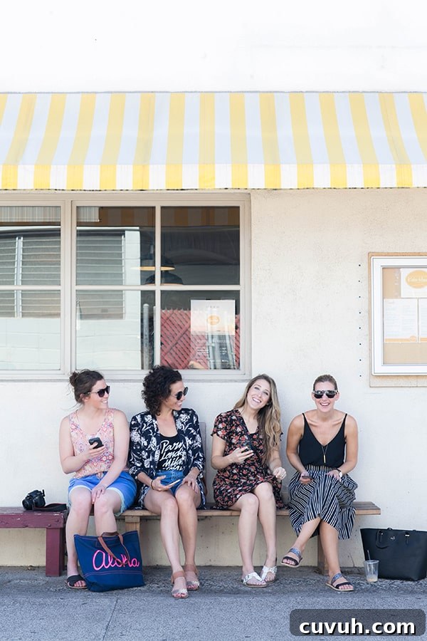 Four girlfriends sitting on a bench outside.