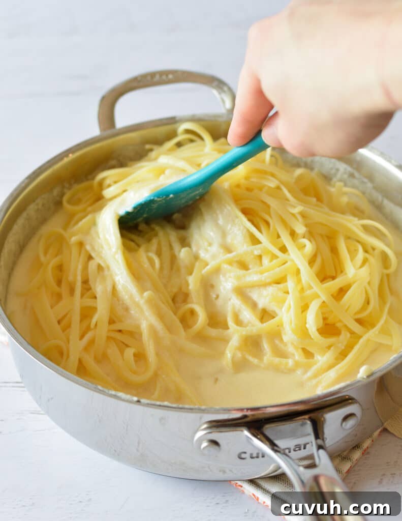 fettucine noodles in a skillet with alfredo sauce. 