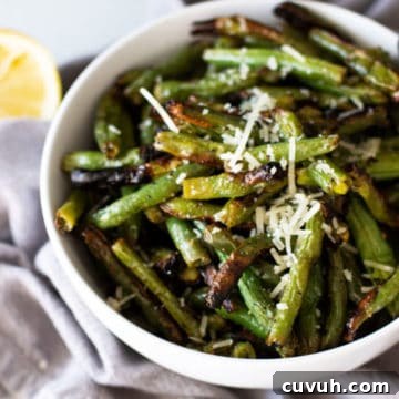 White bowl containing grilled green beans, topped with Parmesan cheese.